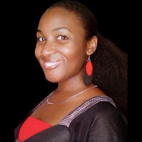 a woman smiling with a black top and red earrings