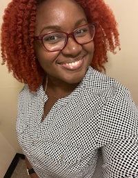 a woman with red hair and glasses smiles for the camera