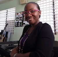 a woman in glasses smiling in front of a keyboard